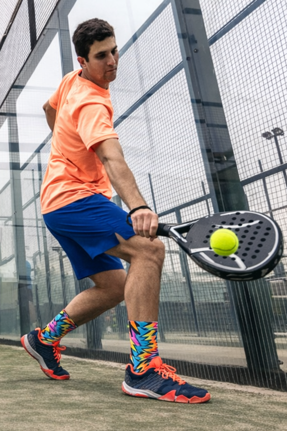 Person playing padel on a court with a racket and ball